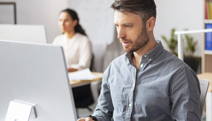 Busy handsome millennial european man manager typing at computer at workplace in modern office interior, copy space. Business, finance planning, data analysis, developing in company and project work